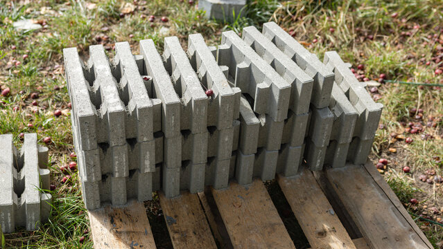 Stack of Gray Interlocking Concrete Paving Blocks on Wooden Pallet Outdoors