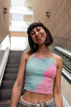 A portrait of a beautiful young woman outdoors. She is wearing colorful clothing and is smiling and laughing.