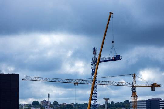 View of construction cranes operating against a cloudy sky in Vilnius, Vilnius County, Lithuania.