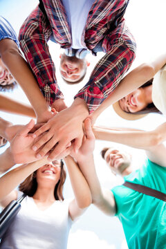 Young friends joining hands in a team huddle showing unity, teamwork, cooperation and friendship outdoors