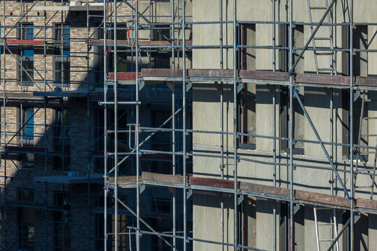 View of a building under construction covered in metal scaffolding with brick and concrete walls in Vilnius, Vilnius County, Lithuania.
