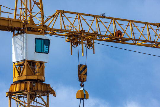 View of a yellow construction crane with a heavy metal hook and pulley system against a clear blue sky in Vilnius, Vilnius County, Lithuania.