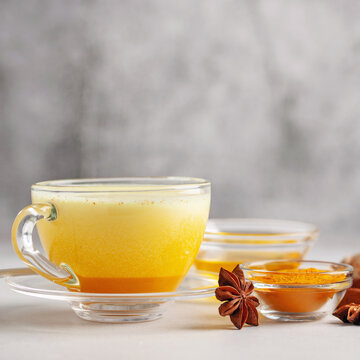 Golden Cinnamon Turmeric Milk. Golden milk with species turmeric, cinnamon, honey and ginger on grey background. Trendy hot Healthy drink . Indian Garam Doodh.