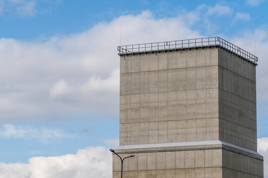 View of a modern concrete tower structure against a blue sky with clouds in Poland.