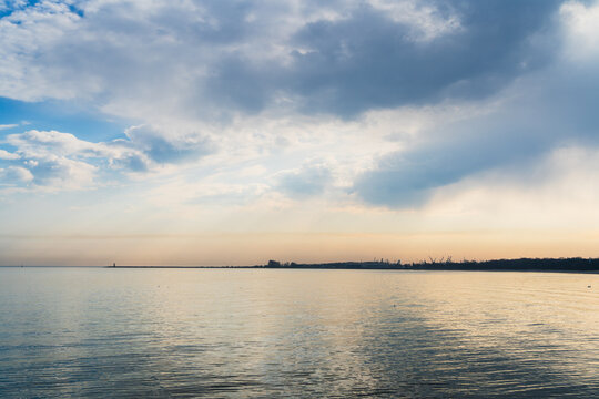 View of the calm Baltic Sea coastline under a dramatic cloudy sky at sunset in Gdansk, Pomeranian Voivodeship, Poland.