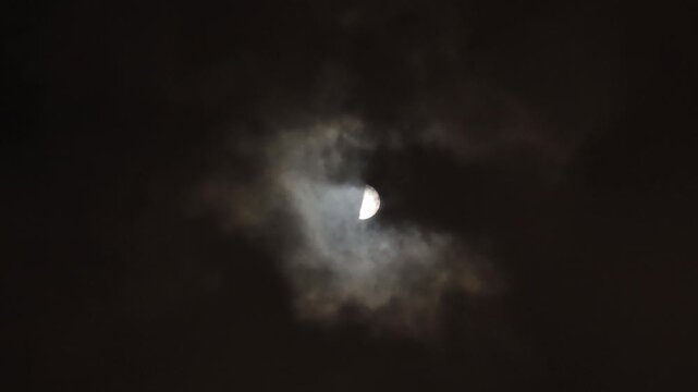Glowing Half Moon Through Dark Clouds at Night