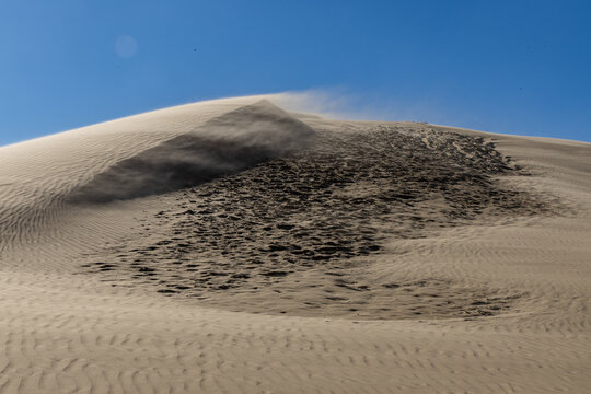 View of the wind-swept sand dunes at Rubjerg Knude with textured sand patterns under a clear blue sky in Lokken, Jutland, Denmark.