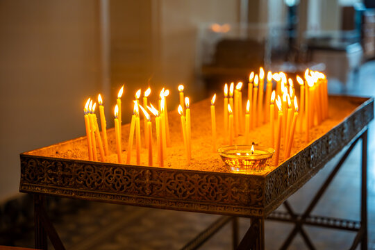 Candles lit on a decorative altar in a church, warm light illuminating the space with a serene atmosphere and intricate metalwork visible