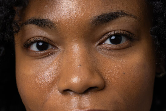 Adult African woman facing camera holding neutral expression in studio close-up showing catchlight