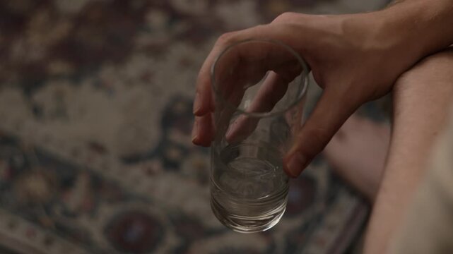 Caucasian young adult man holding empty glass tumbler indoors. Clip suitable for hydration awareness campaigns, healthcare promotions, hangover recovery and wellness content