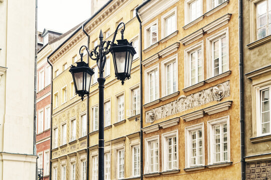 View of a classic black street lamp set against the colorful historic facades of buildings in the Old Town of Warsaw, Masovian Voivodeship, Poland.
