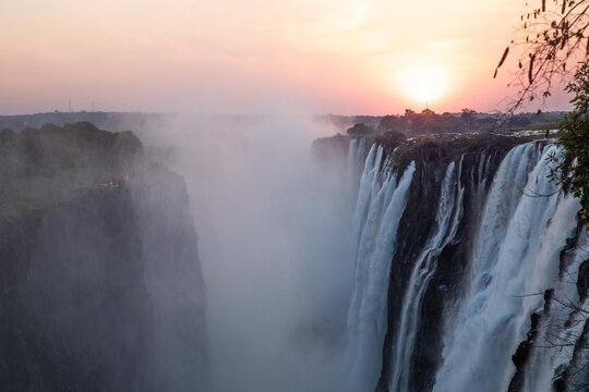 View of Victoria Falls with mist rising from the gorge at sunset in Zimbabwe.