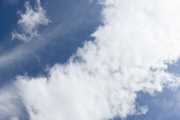 Soft white cumulus and wispy cirrus clouds drift across a vibrant blue sky, conveying calm openness and bright daylight ideal for backgrounds, weather concepts, and nature or travel themes © evannovostro