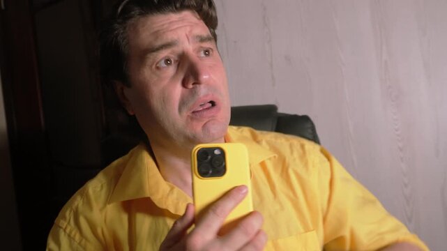 
Close-up of a man emotionally apologizing and asking for forgiveness, holding his hand to his chest while holding a smartphone. 
