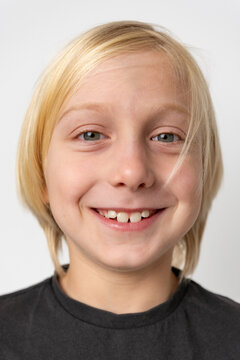 Young blond boy smiling brightly, expressing authentic happiness and innocence, a missing front tooth highlighting his age and the natural process of growing up