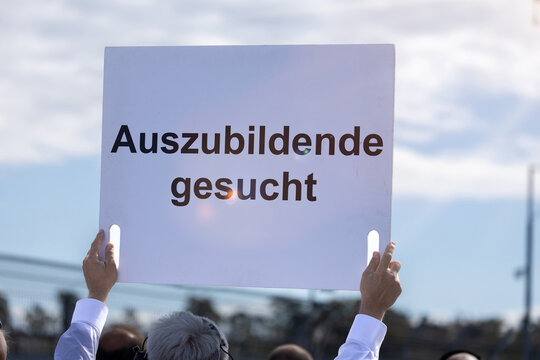 (Fotomontage) Ein Schild mit dem Text AUSZUBILDENDE GESUCHT wird in die H&ouml;he gehalten
