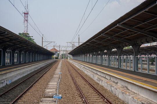 Empty Train Station Platforms with Railroad Tracks and Overhead Wires.