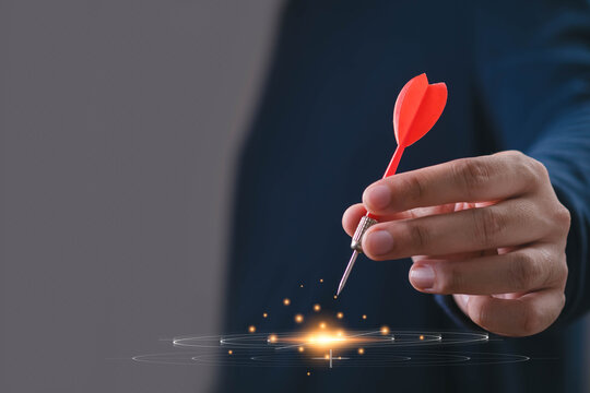 Business strategy concept showing a professional holding a red dart over a glowing digital target, symbolizing focused goals, precision, decision making, leadership, innovation, and successful growth.