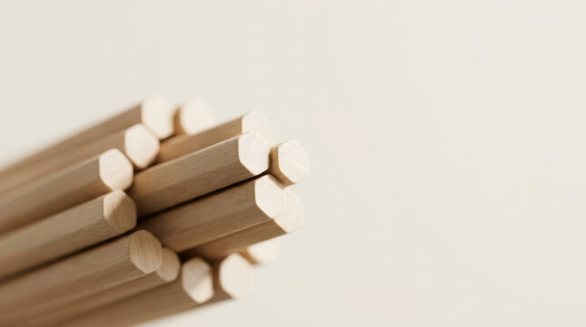 Still life of wooden dowel arranged in bundle with natural wood texture and soft shadow against neutral background