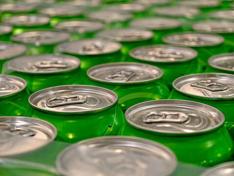 Green aluminum cans of fizzy beverages gathered in packaging on a warehouse shelf, showing a substantial stock of drinks ready for storage and distribution