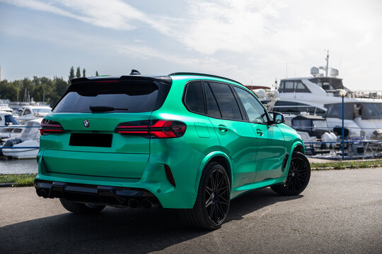 Car Tiffany green BMW X5 parked near luxury yachts and forest background under a clear blue sky. Premium SUV lifestyle photography, vibrant summer atmosphere, modern automotive design