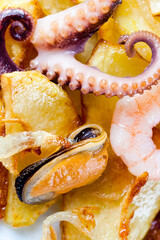 Fried potatoes with octopus shrimp mussels and onion over potato © besjunior