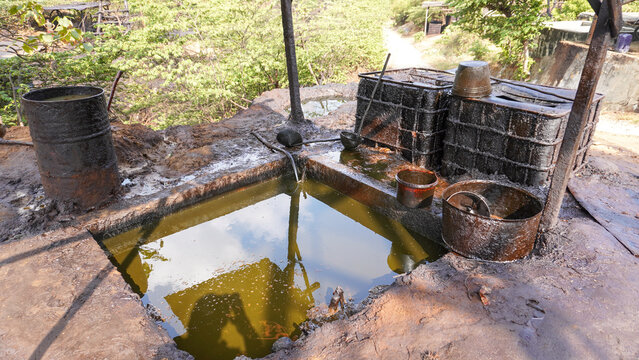 Crude oil reservoir pool and storage tanks at a traditional petroleum mining site in Wonocolo, Bojonegoro, Indonesia. Rural industrial energy extraction, fuel production, and crude processing site.