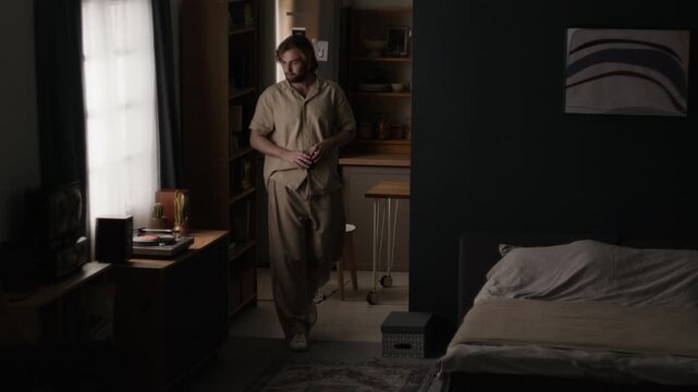 Caucasian young adult man standing up from table and turning on vinyl record player in room. Clip suitable for morning routine campaigns, audio branding and modern lifestyle storytelling