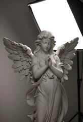 Fototapeta premium Spirituality and faith concept, marble angel statue with praying hands and wings in a studio lighting setup for religious and memorial design projects