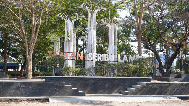 Taman Seribu Lampu landmark sign with decorative white tree structures and lush surrounding trees in Cepu, Blora, Central Java, Indonesia. Famous city park for public travel and tourism.