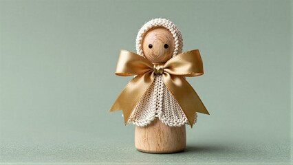 Fototapeta premium Wooden doll with knitted bonnet and golden bow, serene against soft green backdrop.