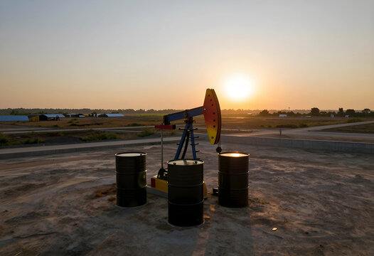 Energy crisis and fossil fuel production, oil pump jack with barrels in a field at sunset global petroleum industry and resource extraction