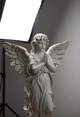 Fototapeta premium Spirituality and faith concept, marble angel statue with praying hands and wings in a studio setting for religious and memorial design projects