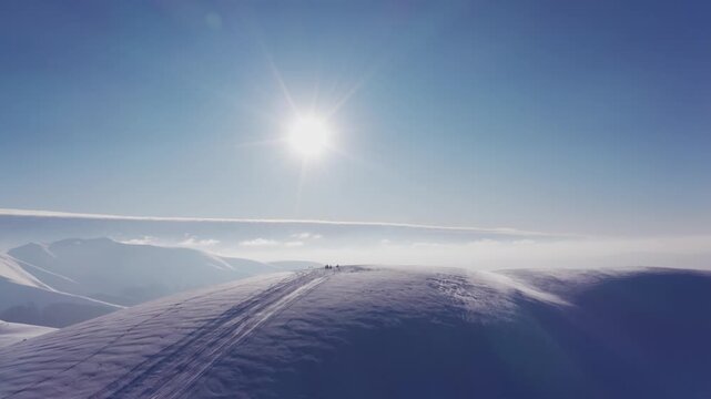 A fast man on a snowmobile rides a deserted slope of a snowy mountain at a bright sunset