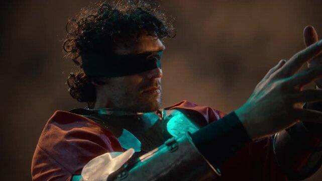 Blindfolded Caucasian young adult man wearing medieval armor moving hands, sensing energy in cave. Footage suitable for fantasy films, action video game promotions, and cinematic trailers
