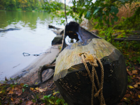 Traditional wooden dugout canoe tied with rope on lake shore