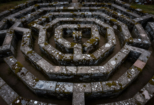Problem solving and strategy, stone labyrinth maze with mossy walls for business challenge, decision making and complexity in a garden landscape