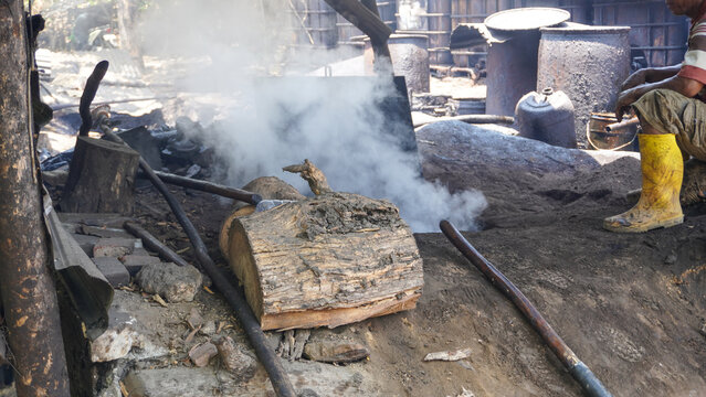 Traditional crude oil refining and distillation process using manual equipment at Wonocolo traditional oil field in Bojonegoro, East Java, Indonesia. Local industrial site producing diesel fuel.
