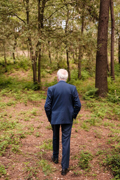 Senior man in suit walking forest path