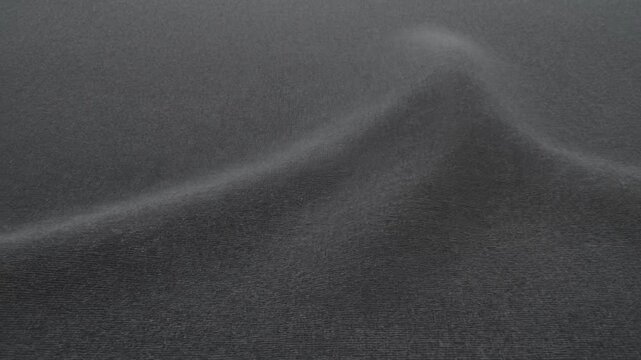 Gray textured fabric surface with subtle curved folds in an abstract close view