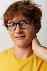 Fototapeta premium A young man wearing glasses and a yellow shirt, posed in a casual portrait with a warm smile, conveying approachable confidence.