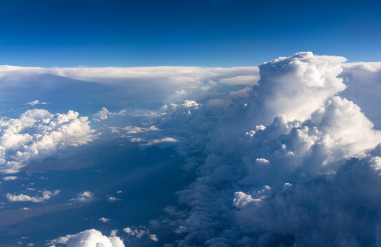 Towering sunlit cloud rising above cloudscape during high altitude flight