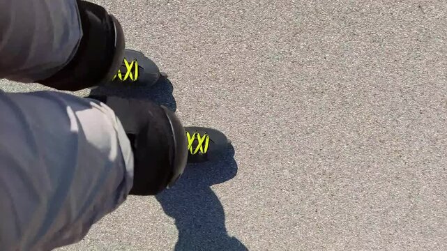 High angle view of feet inline skating on asphalt road, 4K UHD