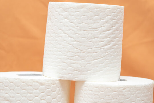 Roll of soft paper towels on  orange background used for cleaning and drying surfaces in homes or businesses. texture that helps absorb spills.  commonly used for cleaning tasks in kitchens, bathrooms