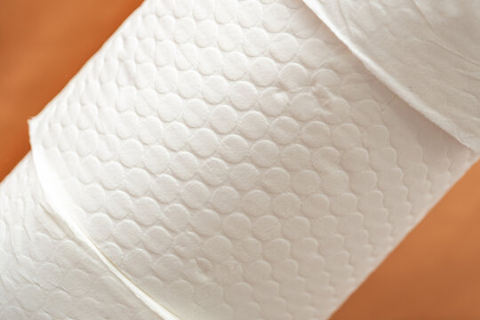 Roll of soft paper towels on  orange background used for cleaning and drying surfaces in homes or businesses. texture that helps absorb spills.  commonly used for cleaning tasks in kitchens, bathrooms