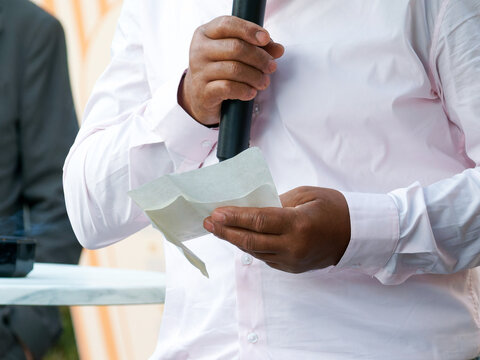 Invit&eacute; lisant un discours de mariage dans ses notes tout en tenant un microphone lors d&rsquo;une r&eacute;ception