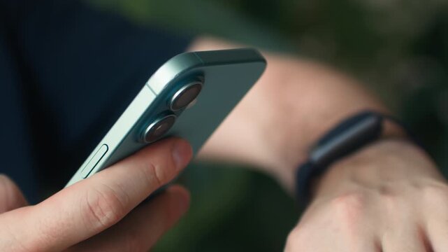 Man using a smart watch on his wrist synced with his smartphone, close-up of male hand touching the touchscreen display