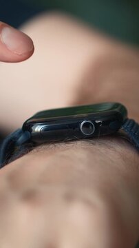 Man using a smart watch on his wrist, close-up of male hand touching the touchscreen display