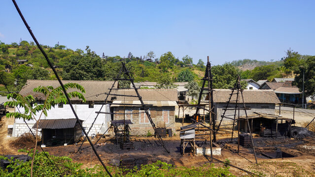 Traditional wooden oil drilling rig structure in Wonocolo, Bojonegoro, Indonesia. Authentic manual crude oil extraction site showcasing heritage petroleum mining, wooden derrick, and blue sky.
