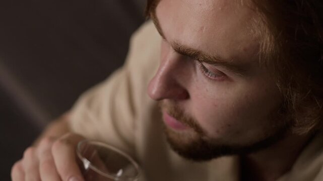 Caucasian young adult man drinking clean water from glass in extreme close up. Footage ideal for healthcare projects, wellness routines, and hydration campaigns